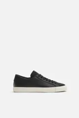 Zapatilla negra de cuero con cordones y detalles en piel serraje.