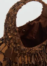 Bolso de mano marrón con flecos y abalorios decorativos.