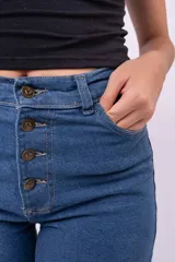 Jean wide leg azul de tiro alto, con cierre frontal de botones expuestos y bolsillos laterales.