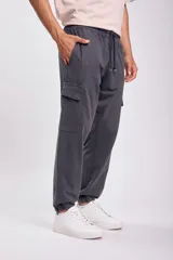 Pantalón deportivo tipo jogger color gris oscuro, con bolsillos cargo laterales, cintura elástica ajustable con cordón y puños elásticos.