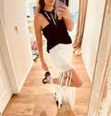 Falda corta de lurex aperlado con flecos y detalles de crochet.