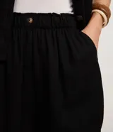 Short blanco de corte runner evasé, con cintura elástica fruncida y un botón decorativo. Presenta bolsillos laterales y un calce suelto.