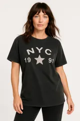 Remera negra con estampado frontal que incluye las letras NYC, el número 1991 y una estrella.