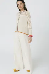 Cárdigan de algodón color crudo, con calce entallado y tejido acanalado. Presenta detalles de crochet hechos a mano, mangas con volados y vivos de color en cuello, puños y frente.