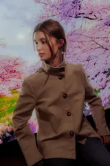 Chaqueta color beige de corte recto, cuello alto estructurado y cierre frontal con botones marrones.