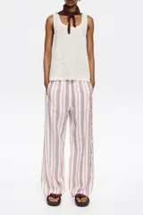 Pantalón de corte jogger con largo tobillero y cintura ajustable con cordón. Diseño a rayas verticales rojas y blancas.