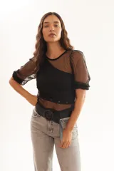 Blusa negra transparente de plumetí con frunces en los hombros y mangas 3/4.