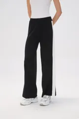 Pantalón ancho de punto color negro con una franja vertical blanca en el lateral.
