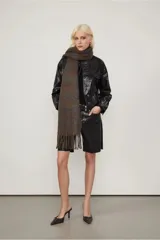 Campera negra efecto vinilo con terminación brillante y cuello redondo acanalado. Presenta bolsillos con solapa en el frente, costuras marcadas y cierre con broches a tono.
