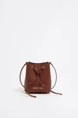 Bolso tipo bucket de cuero color marrón con cierre de cordón ajustable. Tiene correa de hombro delgada y logo de la marca estampado en dorado en el frente.