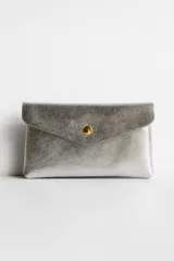 Monedero plateado con textura granulada y cierre con broche dorado.