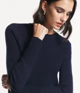Blusa de punto rosa con textura acanalada, cuello redondo y mangas largas.