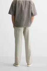 Pantalón color arena de corte recto, confeccionado en tejido de algodón y lino. Cuenta con cintura elástica ajustable con cordón, bolsillos delanteros y traseros de parche.