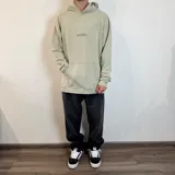 Canguro color gris claro con capucha y cordones ajustables. Estampado en la espalda con un esqueleto de pez, texto "Surf N' Destroy" y otros diseños gráficos.