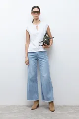 Remera blanca de manga corta con escote en V y detalle de abertura. Presenta un estampado sutil en la parte frontal.