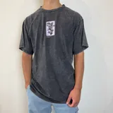 Remera negra con efecto gastado y estampado en la espalda con la frase "The Green House" y un diseño de hojas en color lila.