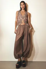 Pantalón bombacho marrón de tejido fluido, tiro medio con cintura elástica ajustable con cordones, bolsillos laterales ocultos y bajo abullonado con elástico interior.