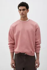 Buzo rosa de tejido liviano de mezcla de algodón con interior cepillado suave, cuello redondo ribeteado, hombros caídos y remate ancho acanalado en puños y bajo. Corte holgado.