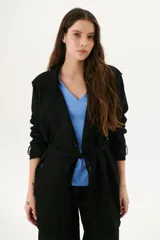 Trench simil gamuza color marrón, con cuello de solapa muesca, cuatro botones delanteros, bolsillos laterales y cinturón a la altura de la cintura.