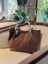 Bolso tote marrón de gamuza, con doble asa de cuero y cierre con lazo.