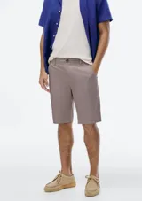 Bermuda estilo chino de hombre, color gris oscuro o carbón, con tiro medio y largo hasta la rodilla. Presenta cierre frontal con botón y bolsillos laterales.