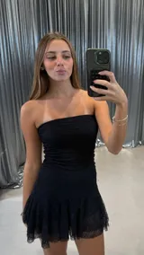 Vestido corto strapless negro de encaje, con cuerpo ajustado y falda con volados.