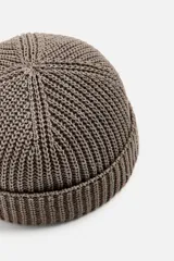 Gorro negro corto de punto con ajuste con trabilla y acabado con vuelta.