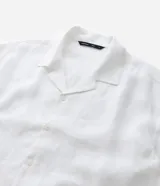 Camisa de hombre de lino blanco, modelo boxy, con cuello bowling y manga corta. Presenta un corte suelto y moderno con abotonado frontal.