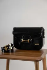 Bandolera color beige con textura símil reptil, cierre con broche metálico dorado y correa larga regulable.