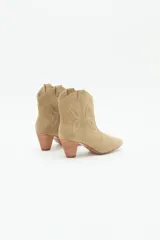 Bota corta de cuero gamuzado color beige, estilo texana, con taco medio de 6 cm y diseño de mariposa en los laterales.