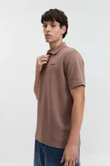 Polo marrón con textura y logo bordado.