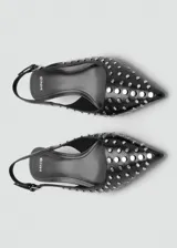 Zapato destalonado negro con tachas plateadas, punta fina, tacón kitten y tira trasera ajustable.
