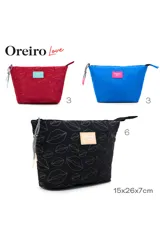 Necessaire de color azul vibrante con textura de labios en relieve. Posee un parche rectangular rosa con el logo "Oreiro Love". Cuenta con un tirador de cierre trenzado en blanco y negro con detalles en rosa.