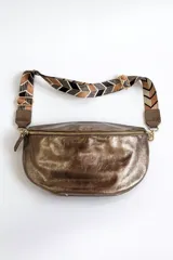 Riñonera color bronce con correa de tela estampada con motivos geométricos en tonos marrones y negros.