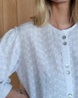 Camisa de mangas largas abullonadas con puños elásticos, cuello redondo y cierre frontal con botones.