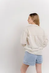 Camisa color crema de algodón con cuello camisero, botones y detalles de encaje en el escote.