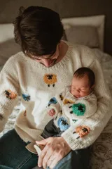 Sweater de lana color crema con cuello redondo y diseño de ovejas de colores bordadas a mano.