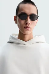 Sudadera con capucha color crudo, corte boxy, manga larga y bolsillo tipo canguro.