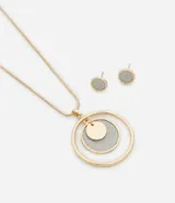 Conjunto de collar largo con cadena fina dorada y colgante de mandala con capas y revestimiento brilloso plateado, acompañado de par de caravanas mini botón brilloso plateado. Producto confeccionado en metal reciclado.