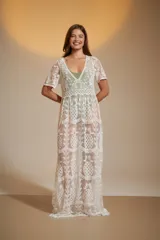 Vestido largo blanco de encaje con diseño de piñas bordadas. Presenta escote en V profundo y mangas cortas holgadas.