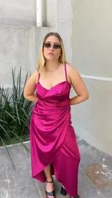 Vestido midi fucsia de satén con escote drapeado, breteles finos y falda cruzada con volados.