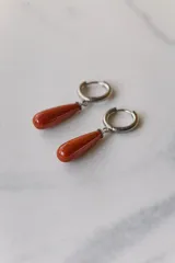 Aros colgantes de acero quirúrgico hipoalergénico con dije de piedra natural en forma de gota color azul oscuro.