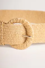 Cinturón ancho color beige, de rafia trenzada, con hebilla redonda metálica.