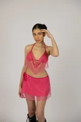 Conjunto de top halter y pollera corta, ambos de red con glitter fucsia. La pollera tiene cordón regulable en la cintura.