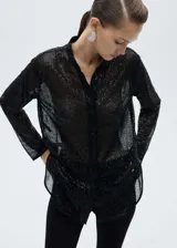 Camisa negra de poliéster con lentejuelas, corte recto, cuello mao y cierre frontal con botones.