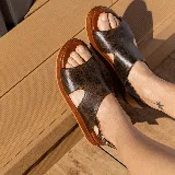 Sandalias plateadas con textura de piel de cocodrilo, con hebilla y suela marrón.