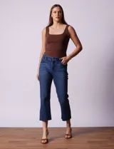 Pantalón jean azul oscuro, tiro alto, corte recto y terminación bootcut. Tiene bolsillos delanteros y traseros, pretina con pasadores, botón y cierre. Aplique de tachas en los laterales.