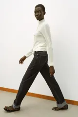 Jeans de tiro alto color negro lavado, con cintura cruzada, cinco bolsillos y pernera recta. El bajo está acabado en vuelta y tiene cierre frontal cruzado con cremallera y botones.