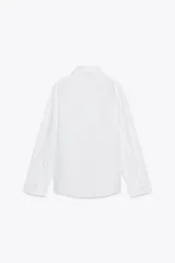 Camisa blanca de cuello solapa y manga larga. Detalle de pliegues con botones. Cierre frontal con botones.