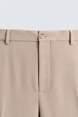 Pantalón de vestir color beige, corte slim fit, confeccionado en tejido con viscosa. Cuenta con bolsillos frontales y traseros de doble vivo con botón. Cierre frontal con cremallera y botón.